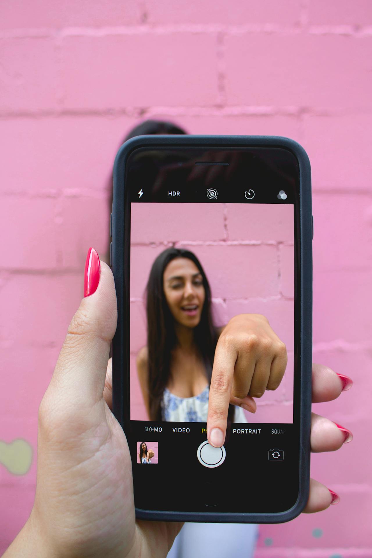 Person looking at a mobile phone screen displaying a slo-mo video with HDR text.